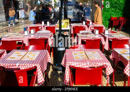 Lisbonne, Portugal - 4 janvier 2023: Restaurant en plein air avec des tables rouges et des personnes marchant autour dans le fond Banque D'Images