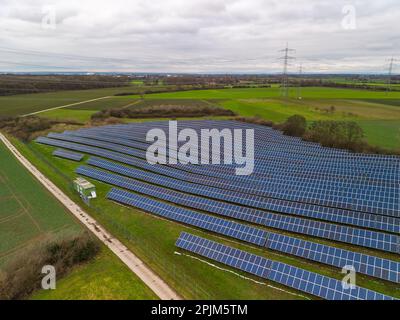 Un parc solaire avec panneaux photovoltaïques sur une piste de ferme au milieu de prairies et de champs dans une région rurale à Hesse, en Allemagne Banque D'Images