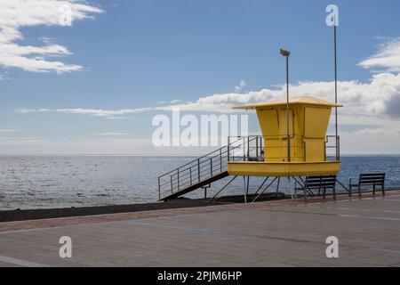 Promenade et tour jaune de maître-nageur sur la plage à côté. Eau calme de l'océan Atlantique en hiver. Ciel bleu avec nuages blancs. Tarajalejo, Fuerteve Banque D'Images