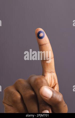 Main de l'homme biracial avec anneau bleu sur le doigt étiré, sur fond gris Banque D'Images
