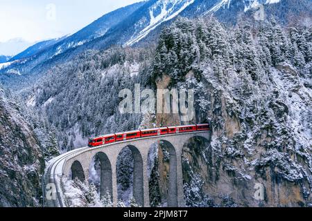 Vue aérienne du train traversant la célèbre montagne de Filisur, Suisse. Landwasser Viaduct patrimoine mondial avec train express dans la neige des Alpes suisses Banque D'Images