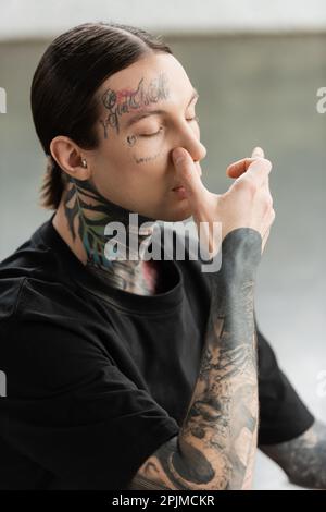 Homme tatoué pratiquant la respiration narine et la méditation dans la classe de yoga, image de stock Banque D'Images