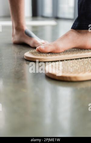 Vue rognée de l'homme pratiquant l'ongle debout sur le tableau de sadhu dans le studio de yoga, image de stock Banque D'Images