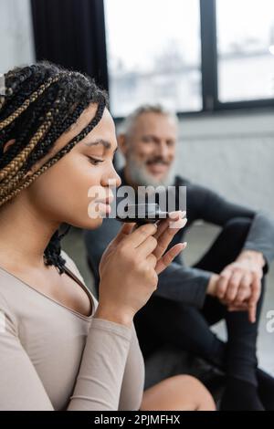 jeune femme afro-américaine avec des dreadlocks qui sent le thé plus pur près de l'homme d'âge moyen sur un fond flou, image de la bourse Banque D'Images