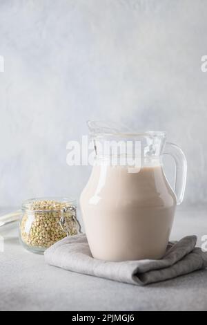 Lait de sarrasin vert dans un pot en verre sur fond gris. Autre produit de remplacement du lait à base de plantes. Format vertical. Banque D'Images