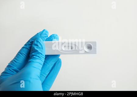 Médecin tenant un test express jetable pour l'hépatite sur fond blanc, gros plan Banque D'Images