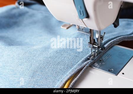 Équipement professionnel. Machine à coudre moderne avec pied de pression spécial. Le processus de couture d'une corde décorative de bordure de bleu article de vêtement. Banque D'Images