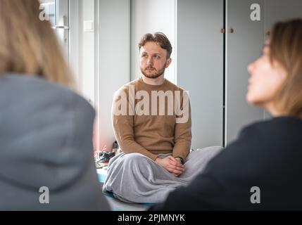 Garçon assis sur un tapis avec une couverture lors d'un cours de yoga ou d'une activité de groupe, d'un renforcement d'équipe, d'un séminaire ou d'un événement Banque D'Images