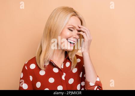 Photo d'une personne âgée heureuse et satisfaite main tactile visage fermé yeux riant isolé sur fond beige couleur Banque D'Images