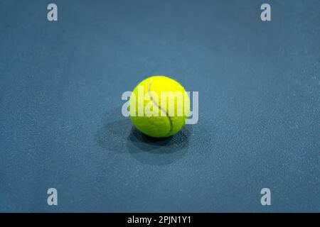 Une photo à plat de la balle de tennis jaune sur fond bleu ou court de tennis. Banque D'Images