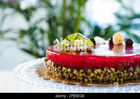 Gâteau à demi-vitrage miroir rouge avec pistache et chocolat sur le dessus Banque D'Images