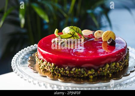 Gâteau à demi-vitrage miroir rouge avec pistache et chocolat sur le dessus Banque D'Images