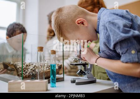 Petit garçon regardant au microscope pendant la leçon de science. Banque D'Images