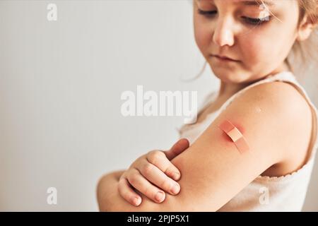 Petite fille sensation de douleur ayant quelques effets secondaires après la vaccination. Rougeur, enflure, membres de la douleur et maux de tête comme réaction après la vaccination. Getti Banque D'Images