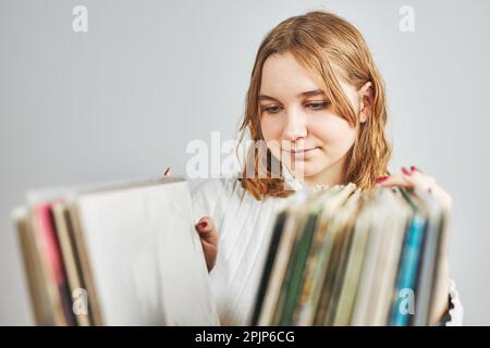 Lecture de disques vinyles. Écouter de la musique à partir d'un lecteur de disques en vinyle. Style de musique rétro et vintage. Jeune femme à la recherche d'un album de LP analogique dans sta Banque D'Images