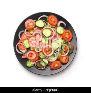 Vue de dessus de la salade de légumes frais de concombre de tomate dans une assiette noire isolée sur blanc Banque D'Images