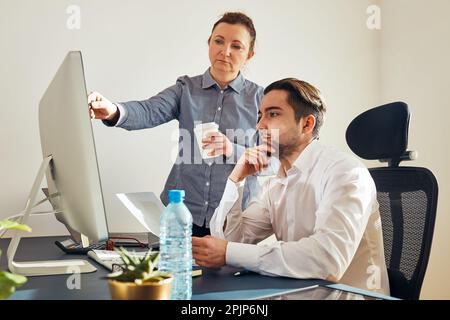 Deux professionnels discutent de données financières sur ordinateur. Femme d'affaires travaillant avec un collègue de sexe masculin au bureau. Les gens entrepreneurs travaillant avec char Banque D'Images