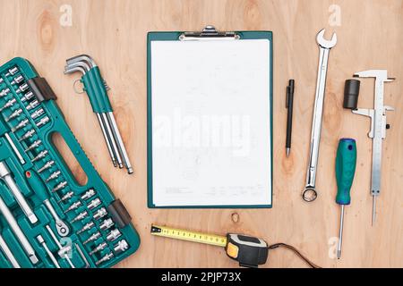 Table d'atelier avec de nombreux outils. Clé, clé, étrier et cliquet avec de nombreux accessoires. Presse-papiers avec papier blanc. Outils de travail. Outil universel se Banque D'Images