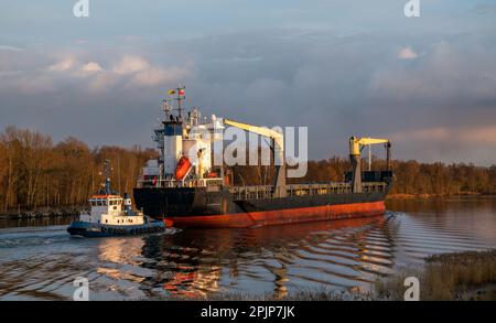 Navire de cargaison entrant dans le port assisté par remorqueur Banque D'Images