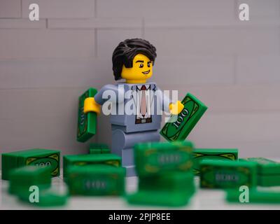 Tambov, Fédération de Russie - 25 mars 2023 Lego homme d'affaires Minifigure détenant deux billets Lego dans un tas d'argent. Banque D'Images