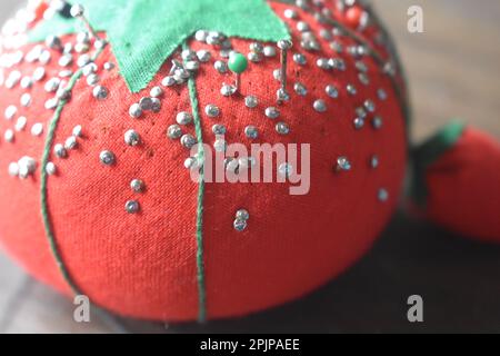 Un coussin de pin vintage pour la couture de broches, un coussin de tomate avec un aiguiseur de broche d'émeri de fraise. Banque D'Images