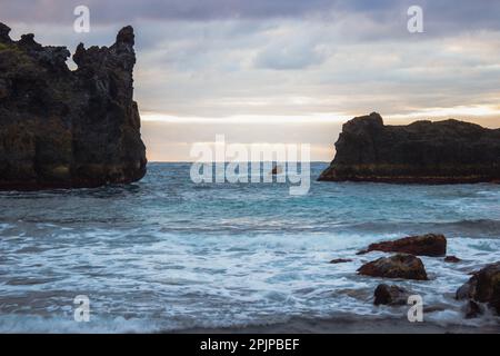 Une plage pittoresque avec une formation rocheuse unique près du rivage, qui claque doucement les vagues visibles en arrière-plan Banque D'Images