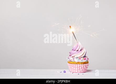 Gâteau d'anniversaire violet et rose avec tourbillon de glace au beurre, saupoudrer et friser sur fond gris clair blanc. copier l'espace. Banque D'Images