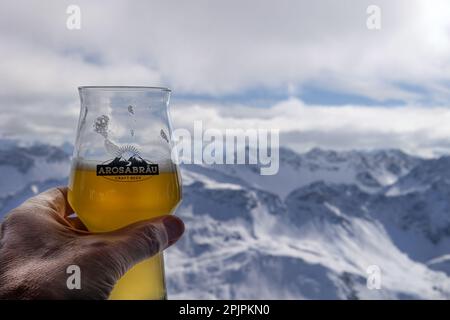 AROSA, SUISSE - 03 MARS 2023 : hlass à la main de la bière artisanale locale Arosabrau sur fond de montagne Banque D'Images