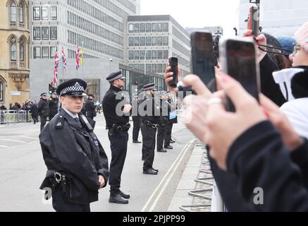 La police fait la ligne et les gens attendent avec leur téléphone mobile, à l'extérieur de l'abbaye de Westminster, à l'approche de la famille royale, à Londres, au Royaume-Uni Banque D'Images