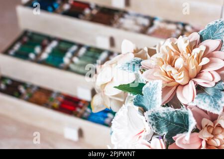 Magnifique boîte pour fils avec compartiments. Magnifiques fils de couleur dans une boîte. Fleurs au premier plan Banque D'Images