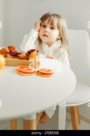 Portrait d'une jeune fille dans une robe de chambre, qui est assis dans la cuisine, à côté d'une boîte de marmelade, fruits confits. Banque D'Images