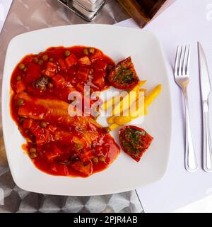 Tilapia cuit avec sauce végétale, pommes de terre et tomates séchées Banque D'Images