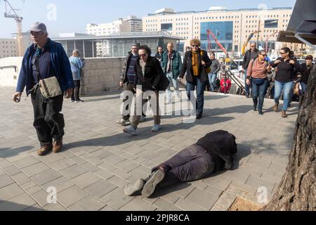 JÉRUSALEM, ISRAËL - 20 février 2023: Un mendiant se trouve sur le trottoir demandant des almes. La foule passe. Gare routière centrale. Banque D'Images