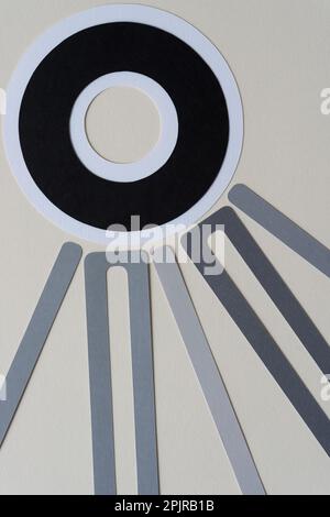 anneaux en papier noir sur blanc et longueurs de papier découpé disposées en forme radiale sur papier vierge Banque D'Images