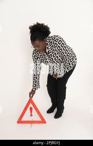 Angleterre, Royaume-Uni. 2022. Une femme pilote plaçant un triangle de danger rouge pour avertir la circulation venant en sens inverse d'une situation d'urgence de conduite, Banque D'Images