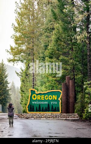 Photo verticale de la femme prenant la photo de l'Oregon vous accueille signe sur HWY 199. Banque D'Images