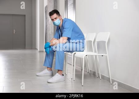 Médecin épuisé assis sur une chaise dans le couloir de l'hôpital Banque D'Images