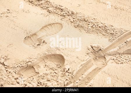 Sable avec empreintes de pas, pistes d'oiseaux et piste de roue Banque D'Images