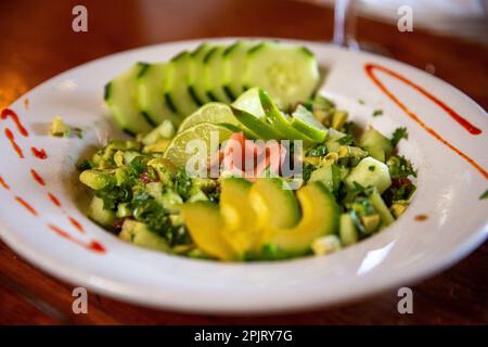 Salade de concombre d'avocat avec un dessin siracha sur l'assiette et le gingembre Banque D'Images