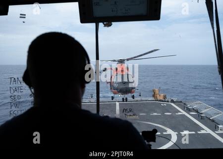 Un membre de l'équipage à bord du coupe-bise Midgett (WMSL 757) de la Garde côtière supervise les opérations d'arrimage d'hélicoptères avec un hélicoptère Dolphin MH-65 de Barbers point de la station aérienne au large d'Oahu, Hawaï, 21 février 2023. Les équipages sont formés pour embarquer et faire le plein d'hélicoptères pendant que le dispositif de coupe est en marche dans diverses conditions météorologiques. (Photo de la Garde côtière par l'officier Petty 3rd classe Briana carter) Banque D'Images