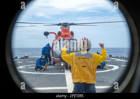 L'équipage du garde-côte Midgett (WMSL 757) effectue des opérations d'arrimage par hélicoptère avec un hélicoptère Dolphin MH-65 de Barbers point de la station aérienne au large d'Oahu, Hawaï, 21 février 2023. Les équipages sont formés pour embarquer et faire le plein d'hélicoptères pendant que le dispositif de coupe est en marche dans diverses conditions météorologiques. (Photo de la Garde côtière par l'officier Petty 3rd classe Briana carter) Banque D'Images