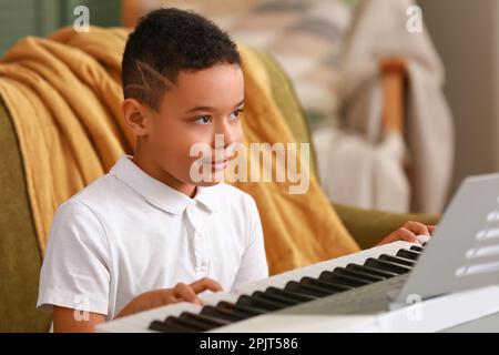 Petit garçon afro-américain jouant au synthétiseur à la maison Banque D'Images