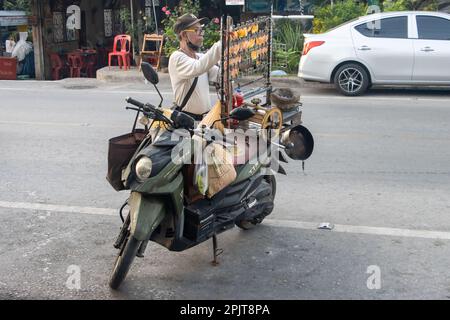 SAMUT PRAKAN, THAÏLANDE, MARS 24 2023, Un vendeur ajuste le calmar pressé séché sur un support monté sur une moto Banque D'Images