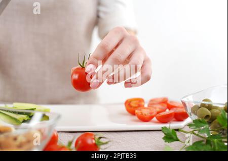 Chef professionnel coupant des tomates fraîches sur une table en marbre blanc dans la cuisine, en gros plan. Photo de haute qualité Banque D'Images