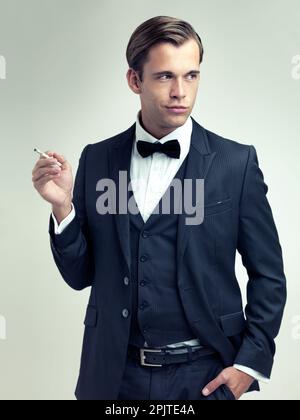 HES ne manque jamais de confiance. Une photo en studio d'un jeune homme qui fume une cigarette. Banque D'Images