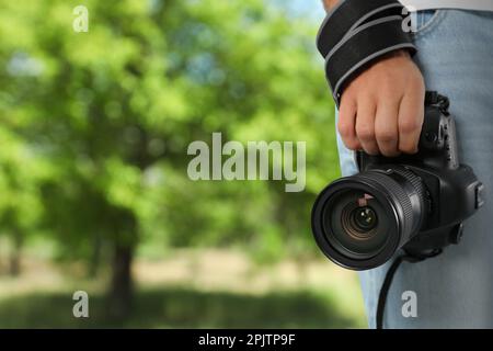 Photographe professionnel avec appareil photo moderne et vue floue du parc, espace pour le texte Banque D'Images