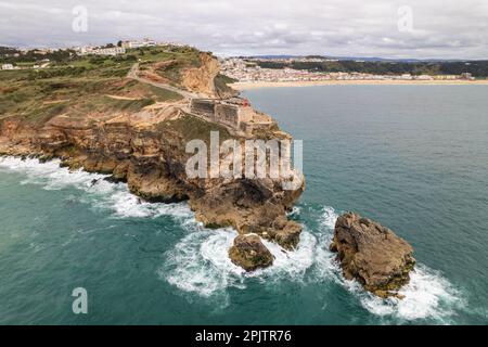 Vue aérienne d'un phare sur une falaise avec une forteresse dans la ville de Nazaré, Portugal Banque D'Images