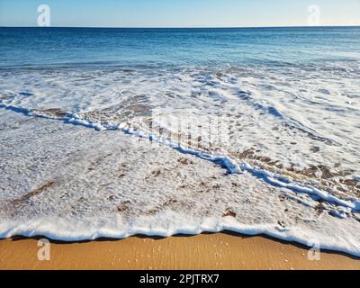 Mousse d'océan couvrant une belle plage de sable. Gros plan. Banque D'Images