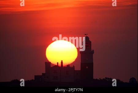 Le soleil se lève derrière le phare de l'île de Coquet qui se trouve à 1,2 km de la côte de Northumberland près de la ruée et devient une ruche d'activité avec jusqu'à 35 000 oiseaux de mer qui utilisent l'île. Date de la photo: Mardi 4 avril 2023. Banque D'Images