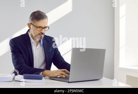 Un homme d'affaires sérieux et concentré sur le lieu de travail est engagé dans le calcul des finances de son entreprise. Banque D'Images